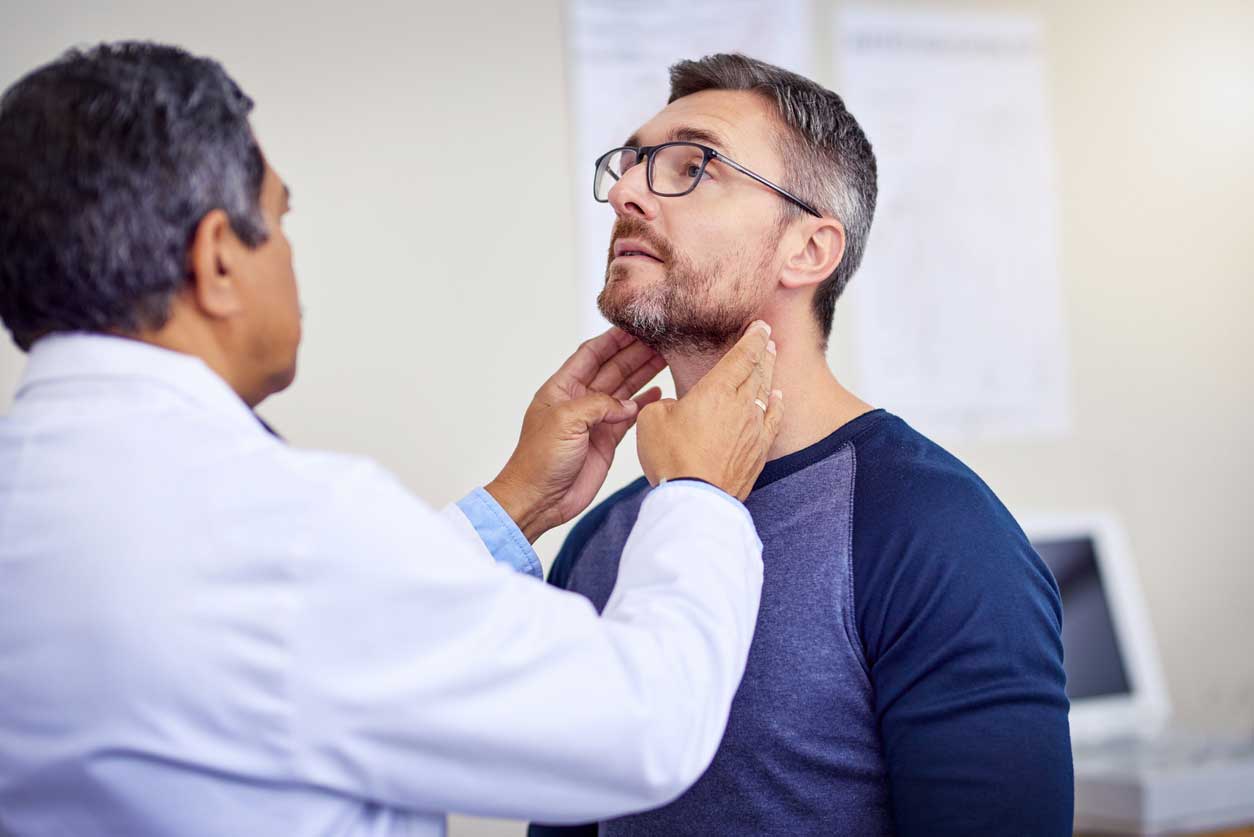 Confident male doctor examining a patient for neck pain during a hospital checkup