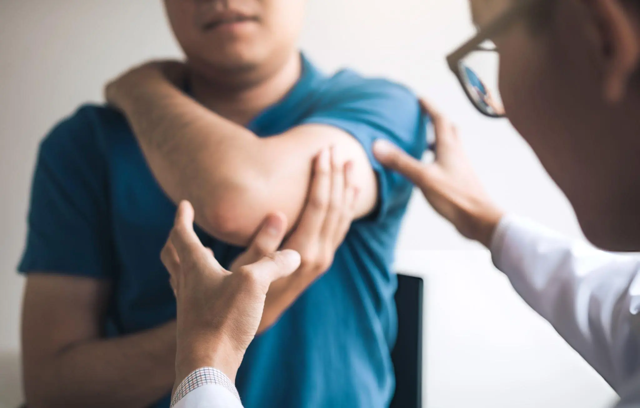 Healthcare professional examining patient’s shoulder—representing conventional therapies for ankylosing spondylitis including NSAIDs, PT, and biologics