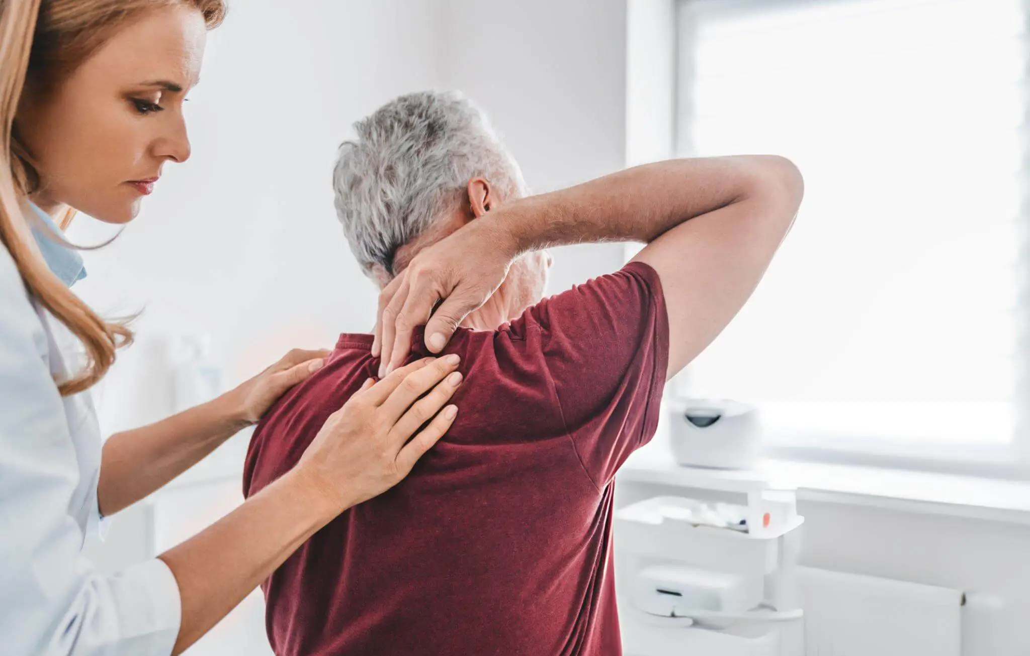 Healthcare professional assessing elderly patient’s upper back—representing widespread burden and chronic nature of low back pain